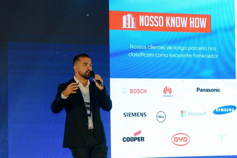 Apresentação da DMEGC Solar no palco, diante do slide “Nosso know how” com os clientes da marca